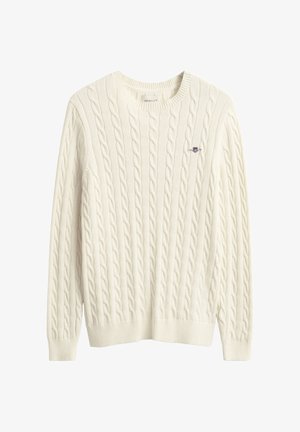 Pull crème en maille torsadée avec col rond et bordures côtelées. Petit logo bleu brodé sur la poitrine. Tissu doux et texturé.