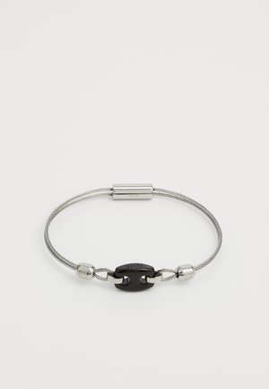 Bracelet made of grey cable with a black metal clasp. Features two metallic accent pieces on either side of the clasp.