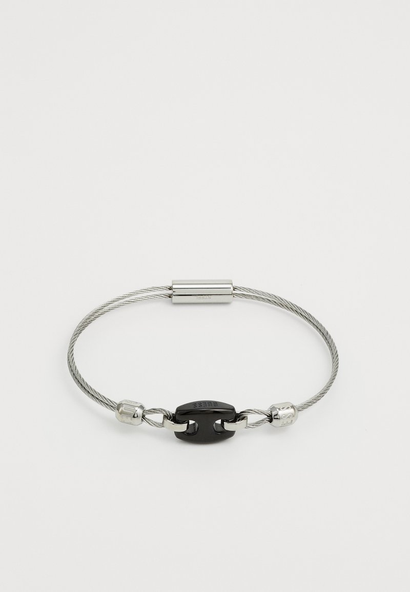 Szürke kábelből készült karkötő fekete fémcsattal. Két fém díszítőelem található a csat két oldalán.