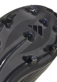 Suola di scarpa da calcio nera con tacchetti moldati, scanalature lineari e dettagli superficiali texturizzati. Presenta design di tacchetti triangolari e circolari.