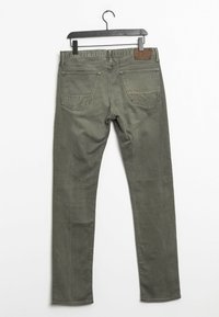 Olivově zelené džíny slim fit, pět kapsových design, a kovové detaily. Mají koženou nášivku na zadním pásku. Hladká textura.