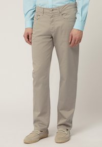 Bežani pantaloni od bavulje s ravnim krojem, prednjim džepovima i klasičnim kopčanjem na dugme. Glatka površina i minimalni detalji šivanja.