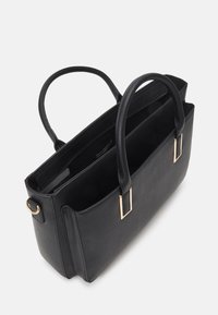 Sort læderstor taske med gyldne metaldetaljer, der har to håndtag, et rummeligt indre og opdelte rum til organisering.