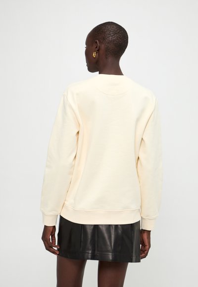 Lysbeige sweatshirt med rund hals og lange ærmer. Lavet af blødt materiale, har ribbede manchetter og kant. Bær den med en sort miniskirt.