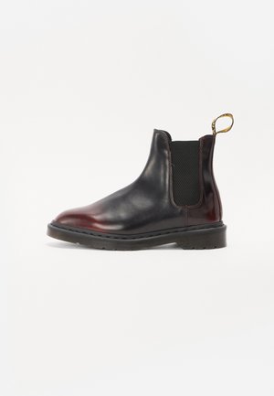 Zwarte en bordeaux leren chelsea boot met elastische zijpanelen, een gestructureerde rubberen zool en een aantrekflap aan de hiel.