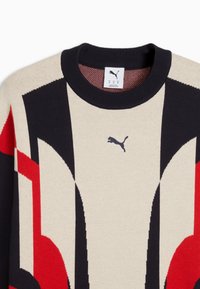 Maglione con scollo a girocollo nero, caratterizzato da motivi geometrici astratti in nero, rosso e beige, e un piccolo logo Puma nero centrato sul petto.