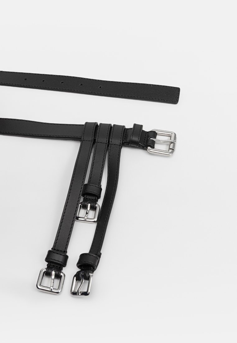 Cintura in pelle nera con molteplici cinturini, ciascuno con fibbie in metallo argentato. Il design include lunghezze regolabili per una maggiore versatilità.