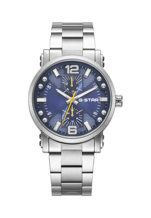 Montre-bracelet en métal argenté avec cadran bleu, grands chiffres 12 et 6, logo G-STAR, et aiguilles jaunes des secondes et du sous-cadran indiquant 10:10:34.