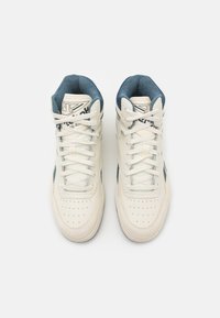 Höga sneakers i off-white läder med blåmocka accenter och perforerad tå. Utrustad med vita snören och logotyp på tungan.