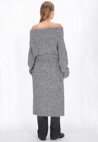 Pulover gri tricotat, cu maneci lungi si umeri goi, cu un cordon in talie, avand o textura moale si o silueta dreapta, care ajunge la jumatatea gambei.