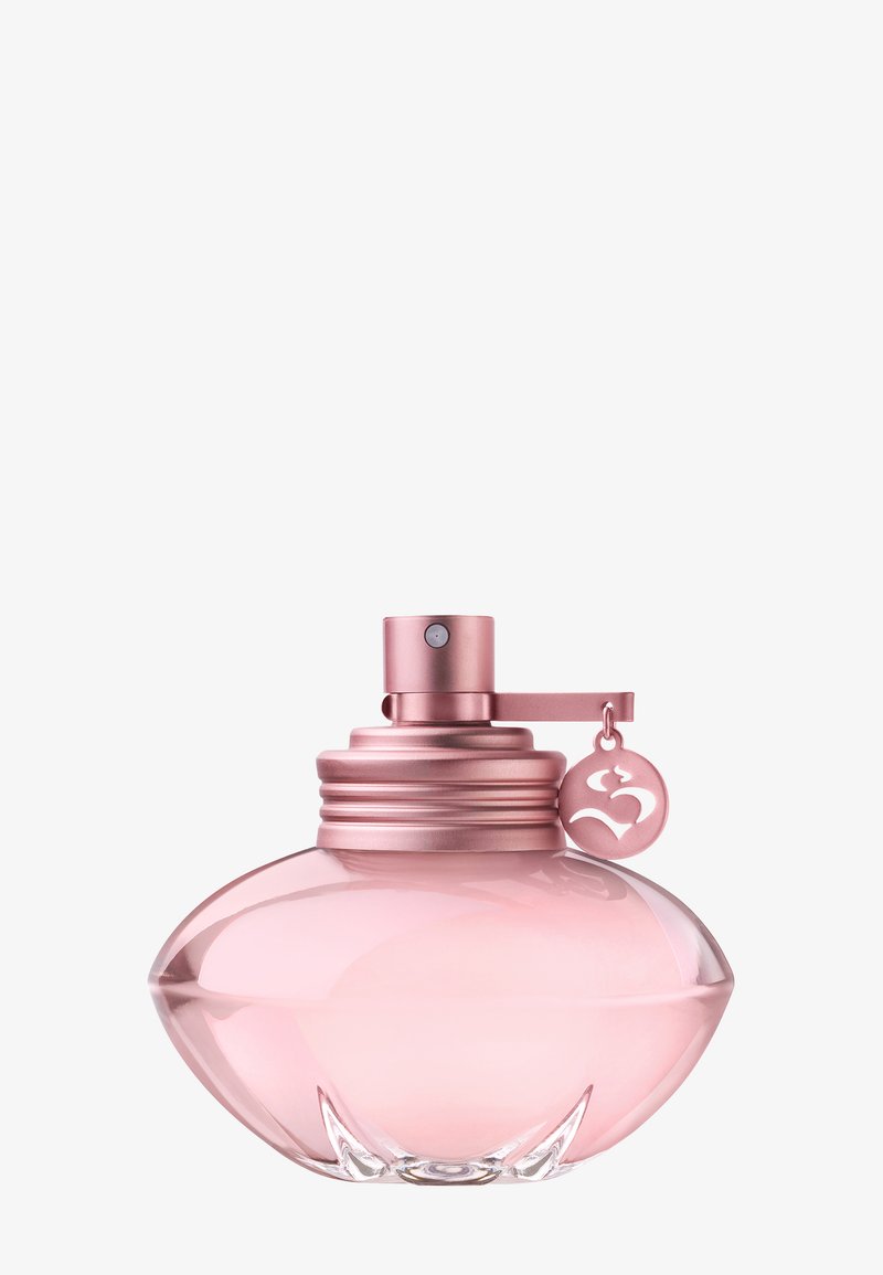 Transparante lichtroze afgeronde parfumfles met metalen roze spraydop en hangende cirkelvormige bedel tegen een witte achtergrond.