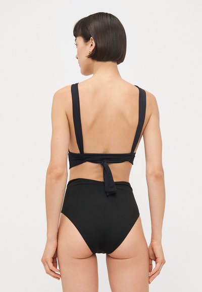 Melnas bikini komplekts ar aizmugurē sasienamu topu, kuram ir platai sānu siksnām, un augstas vidukļa biksēm. Gluda tekstūra, minimālists dizains un vienkrāsains.