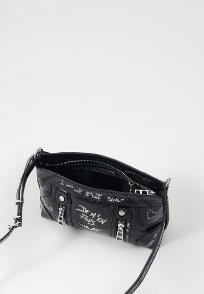 Crni sintetički crossbody ranac s grafitnim bijelim tekstom, dva zip zatvarača i srebrnim metalnim detaljima.
