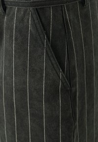 Schwarz gestreifter Stoff mit feinen weißen Vertikallinien, weicher Textur und maßgeschneidertem Design. Mit Seitentasche.