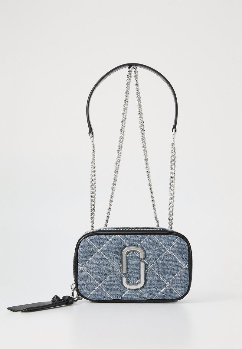 Bolsa transversal em denim com um padrão matelassé, detalhes em couro preto, alça de corrente prateada e um destacado logotipo na frente.