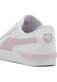 Białe skórzane sneakersy z różowym paskiem PUMA, gumową podeszwą i wyściełanym kołnierzem. Posiadają markowe akcenty na pięcie i boku.