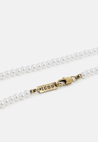 Colar de pérolas brancas com contas redondas brilhantes, apresentando um fecho dourado com a gravação "ICON". Design simples e elegante.