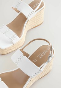 Witte wedge sandalen met brede banden met gestikte details, een gevlochten jute tussenzool en een verstelbare enkelriem.