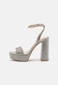 Silberne Plattform-Sandalen mit einem breiten Riemen, verziert mit Strasssteinen. Mit einem Blockabsatz und einem Knöchelriemen mit Schnalle.
