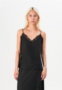 Black camisole featuring adjustable spaghetti straps, a V-neckline with lace detailing, and a smooth satin finish. Simple, relaxed fit.