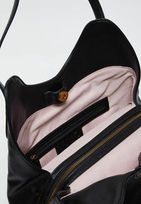 Sac à main en cuir noir avec un intérieur rose. Ses caractéristiques incluent une poche zippée et une fermeture magnétique. Extérieur texturé avec doublure lisse.