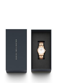 Rose gold wristwatch with a white dial, metal link band, and minimalist markers, presented in a navy box with black cushioning.