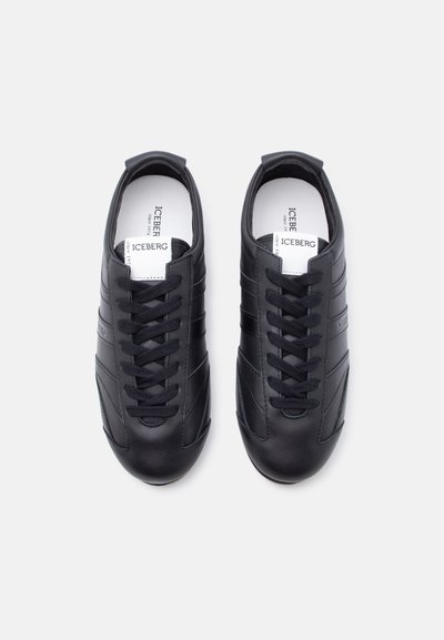 Paire de baskets en cuir noir avec des lacets noirs et des semelles intérieures blanches portant la marque "ICEBERG" sur un fond clair uni.