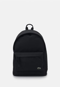 Mochila negra hecha de tejido duradero, con una parte superior curva, bolsillo frontal con cremallera y un logo sutil en la parte delantera. Textura suave.