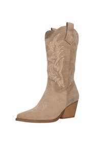 Bota de cowboy de ante beige con punta puntiaguda, diseño floral bordado y tacón apilado. Cuenta con lengüetas para facilitar su puesta.