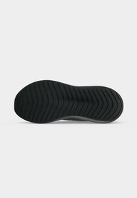 Semelle de chaussure noire avec des rainures horizontales pour l'adhérence, présentée à plat sur fond blanc.