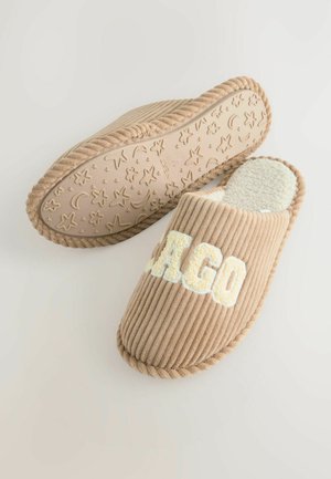 Beige kordfløjlsslapper med ribbet tekstur og blødt indre. Har 'AGO' bogstaver og et mønstret gummisål med stjerner og måner.