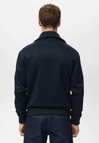 Maglione blu navy con collo a camicia, polsini e orlo a coste. Realizzato in tessuto morbido, presenta una vestibilità comoda e una texture liscia.