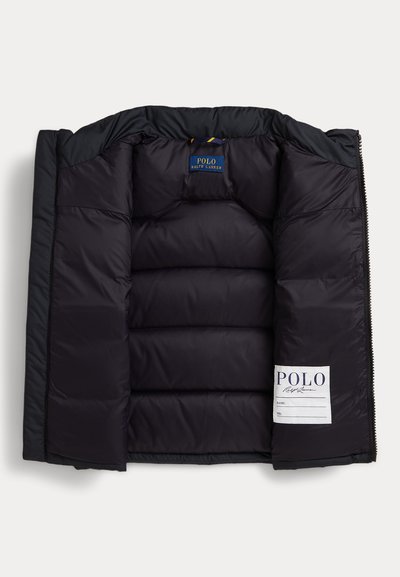 Interior de uma jaqueta preta acolchoada com seções acolchoadas, um rótulo de marca azul e uma etiqueta de cuidados branca com detalhes em texto preto.