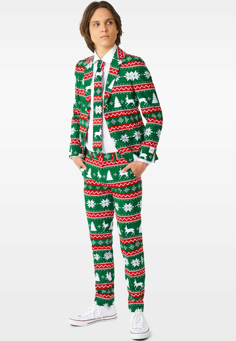 Grøn juledragt med mønstre i hvidt og rødt, som viser træer, snefnug og rensdyr. Hvid skjorte og slips med samme design.