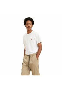 Camiseta de algodón blanca con un pequeño logo rojo, combinada con pantalones beiges de cintura elástica y cordón verde oscuro.