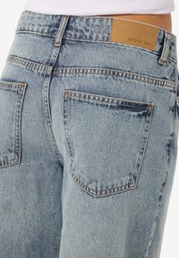 Φωτεινό γαλάζιο τζιν από denim πίσω με δύο τσέπες και καφέ δερμάτινη ετικέτα μάρκας με την ένδειξη "NOISY MAY" στη μέση.