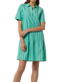 Kurzes Kleid mit Kragen in Türkis, mit vertikalen weißen Streifen und einem gestuften Saum, aus einem leichten Stoff mit glatter Textur.