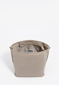 Beżowa torba na ramię o gładkim, matowym wykończeniu, wyposażona w zamknięcie na suwak, wewnętrzną przegródkę oraz widoczną metkę marki wewnątrz.