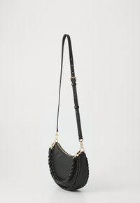 Sac à main en cuir noir avec une forme incurvée, une poignée tressée, des accents en métal doré et une bandoulière réglable. Texture lisse.
