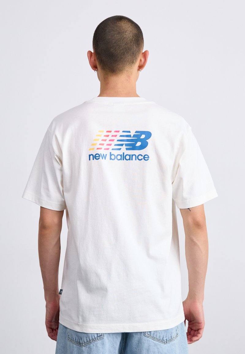 Tricou alb din bumbac, cu un logo mare multicolor "New Balance" pe spate, croială lejeră și mâneci scurte. Design simplu.