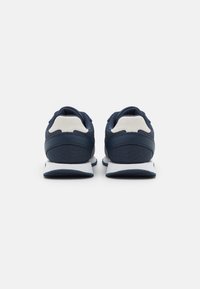 Scarpe da ginnastica blu navy con tomaia in tessuto testurizzato, colletto imbottito, suola in gomma bianca e accenti grigio chiaro in contrasto sul tallone.