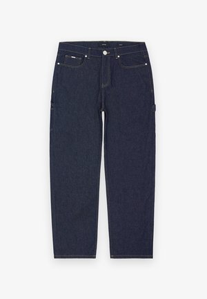 Tummansiniset denim-farkut, joissa on suora leikkaus. Niissä on näkyvää keltaista ommelta, etu- ja sivutaskuja sekä metallinen nappisuljenta.