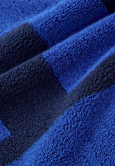 Μπλε πετσέτα με διάφορες αποχρώσεις του μπλε και ναυτικού, με υφή και ρίγες που δημιουργούν ένα μοτίβο.
