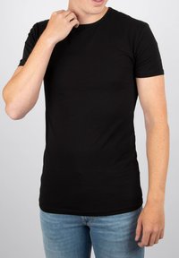 Zwarte, kortemouwen t-shirt van zacht katoen. Heeft een ronde hals en een slim fit, gedragen met blauwe jeans.