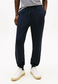 Navy blå sweatpants lavet af blødt bomuldsmateriale, med elastisk talje med snøre, sidelommer og tætsiddende manchetter.