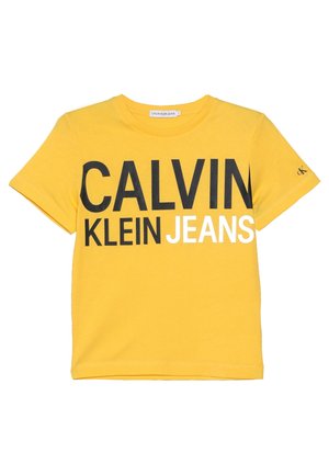 Żółta bawełniana koszulka z wyrazistymi czarno-białymi grafikami z napisem „CALVIN KLEIN JEANS” na przodzie oraz małym logo na rękawie.
