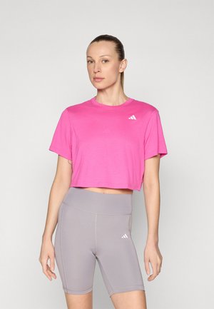 Pink cropped t-shirt with short sleeves and white logo, paired with gray high-waisted bike shorts featuring matching logo and stitching details.
