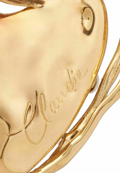 Accessorio a forma di cuore in oro con superficie liscia, incisa con "Claudie" e dettagli intricati a forma di rami lungo i bordi.