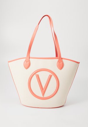 Canvas tote bag met koraal leren afwerking, voorzien van een opvallend rond logo, brede vorm en twee stevige handgrepen. De textuur is geweven en glad.