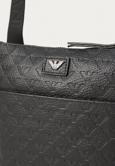 Geantă din piele texturată neagră cu un model repetitiv al logo-ului, un accent metalic cu logo și un închidere cu fermoar în partea de sus.